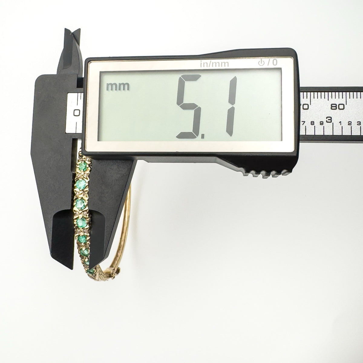 Caliper measuring bangle width at widest point of gemstone setting