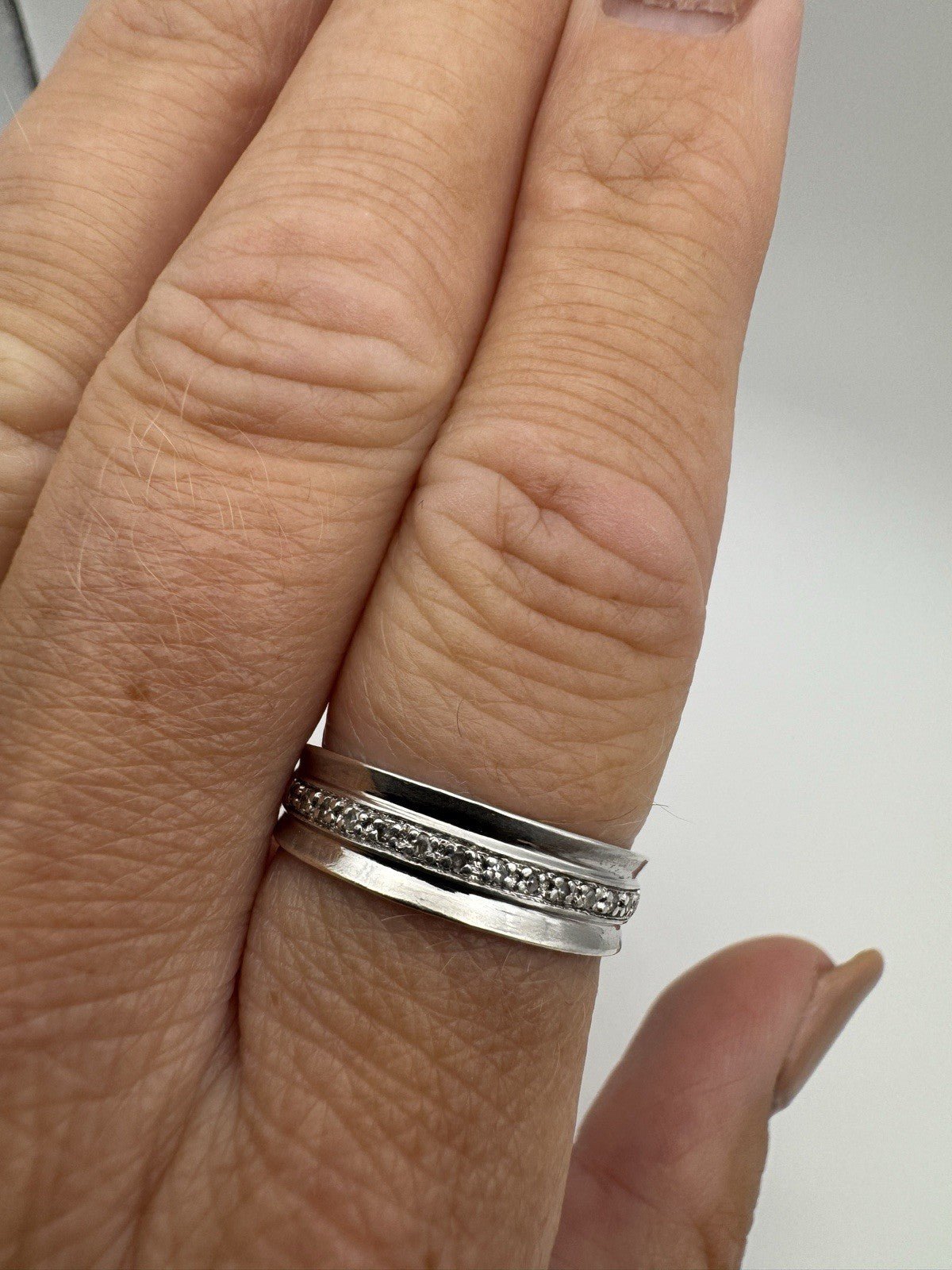 Close-up of sterling silver diamond ring worn on finger, showing flush claw setting