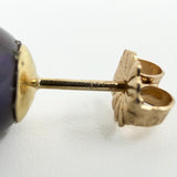 Macro view of a 9ct gold earring post stamped 375 beside a cultured black pearl
