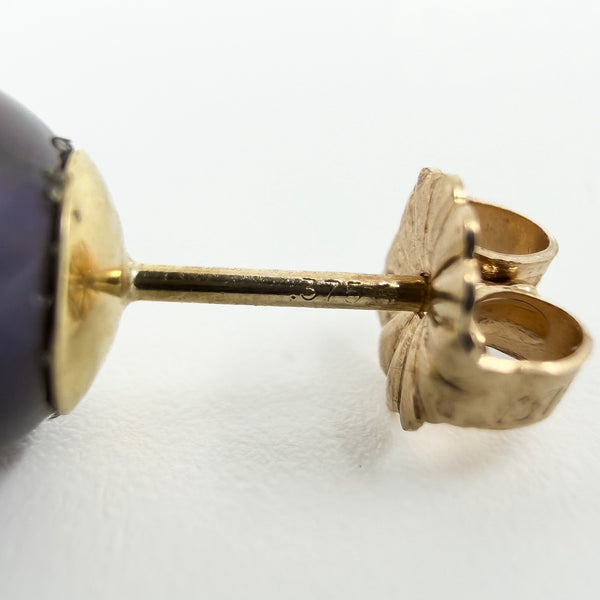 Macro view of a 9ct gold earring post stamped 375 beside a cultured black pearl