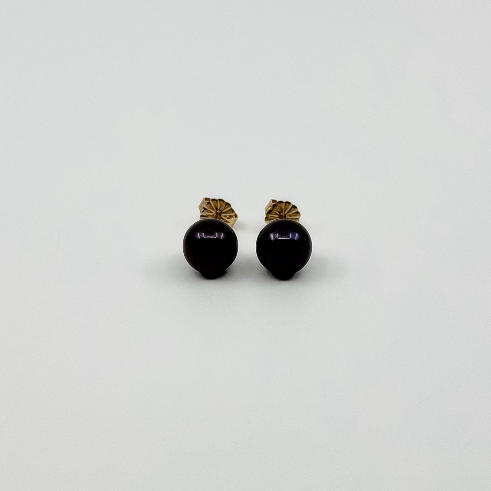 Vintage 9ct gold cultured black pearl stud earrings shown from the front with butterfly backs