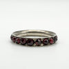 Angled close-up of garnet-set silver ring showing the row of hand-cut stones
