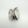 Vintage locket partially open to show both engraved panels and bail