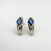Angled view of chunky half hoop earrings set with vivid blue CZ stones