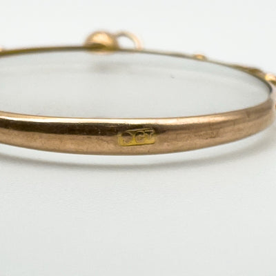 Close-up of 9ct gold hallmark stamp on edge of antique glass locket pendant.