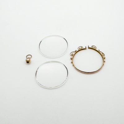 Disassembled gold locket showing two glass inserts and frame