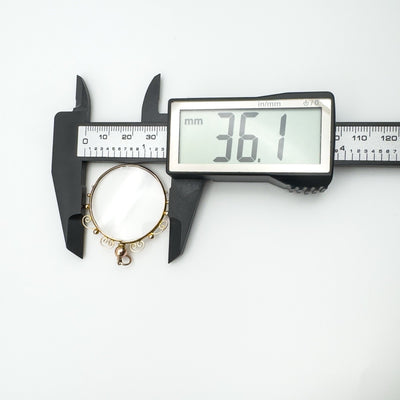 Caliper showing external width of gold locket frame