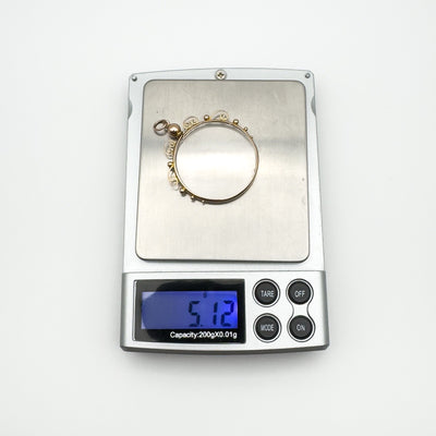 Gold and glass keepsake locket shown on digital scale