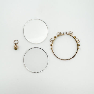 Disassembled antique 9ct gold glass locket showing frame, glass inserts, and screw-top bail.