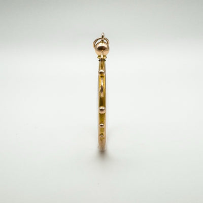 Slim profile view of antique 9ct gold locket showing beaded frame design.