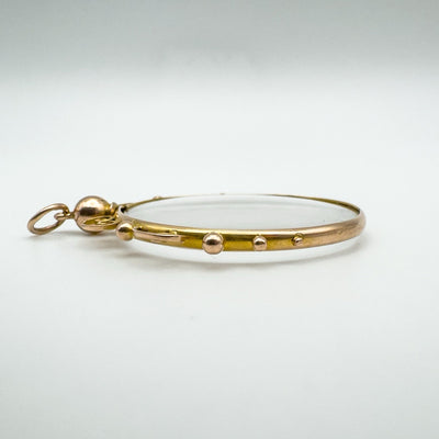 Side view of 9ct gold glass locket pendant showing domed shape and gold dots.