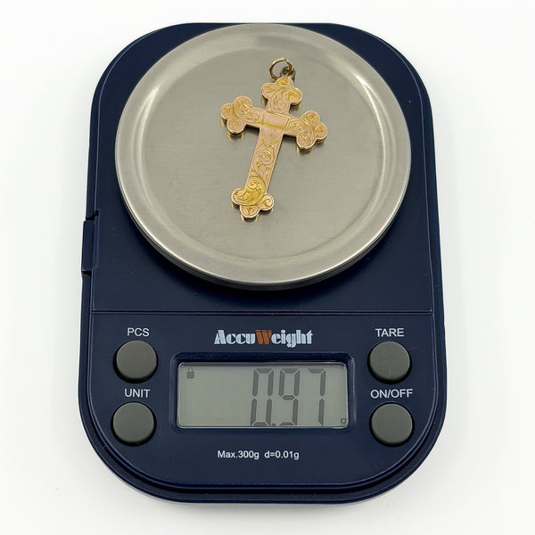 Antique 9ct rose gold cross pendant shown on weighing scales at approximately 0.9g