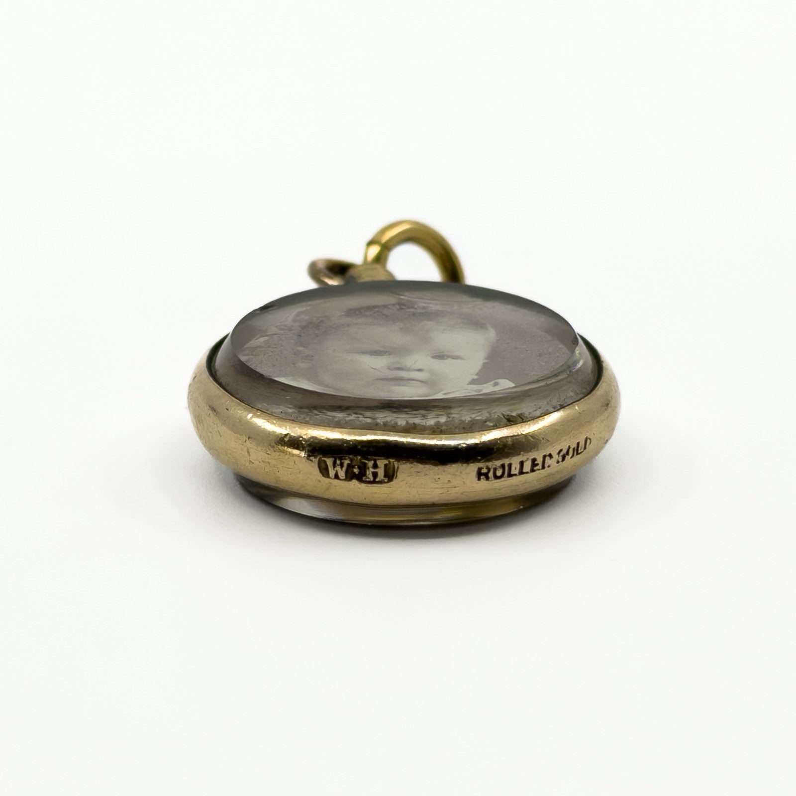 Side view of antique rolled gold double sided glass photo locket with bail and rounded case