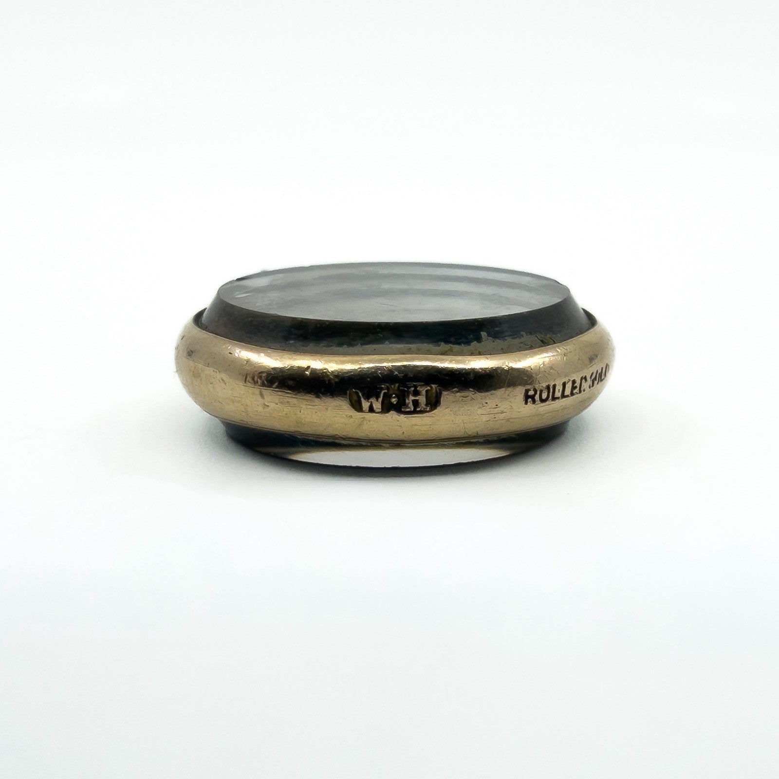 Low side view of antique rolled gold glass photo locket showing its rounded frame and domed glass