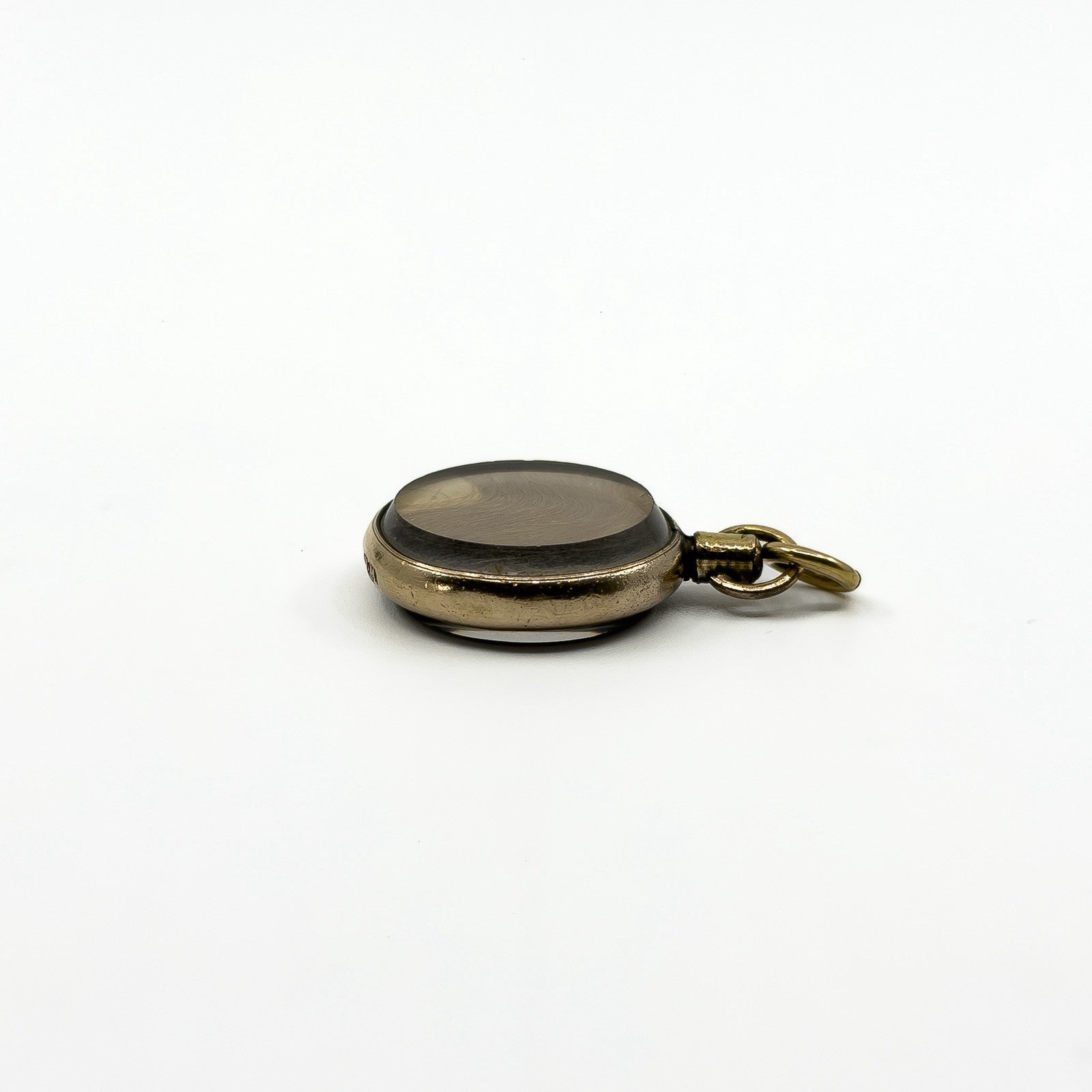 Side profile of an antique rolled gold double sided glass photo locket with domed glass panels