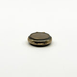 Close view of antique rolled gold glass photo locket with edge stamp detail and domed glass