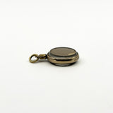 Close side view of antique rolled gold photo locket showing the stamp and original portrait under glass