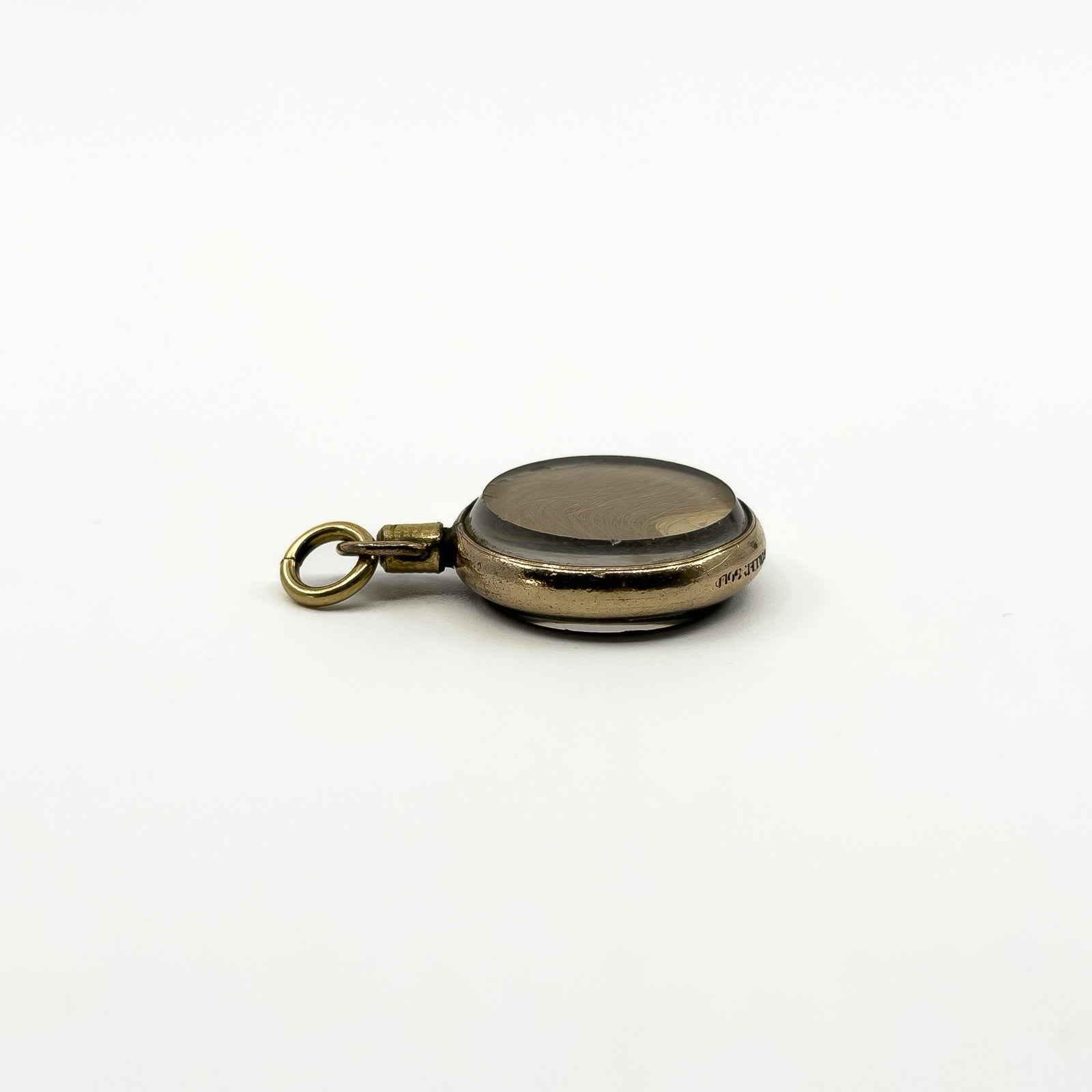 Close side view of antique rolled gold photo locket showing the stamp and original portrait under glass
