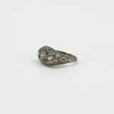 Angled side view of Art Deco platinum diamond trilogy ring with filigree detail