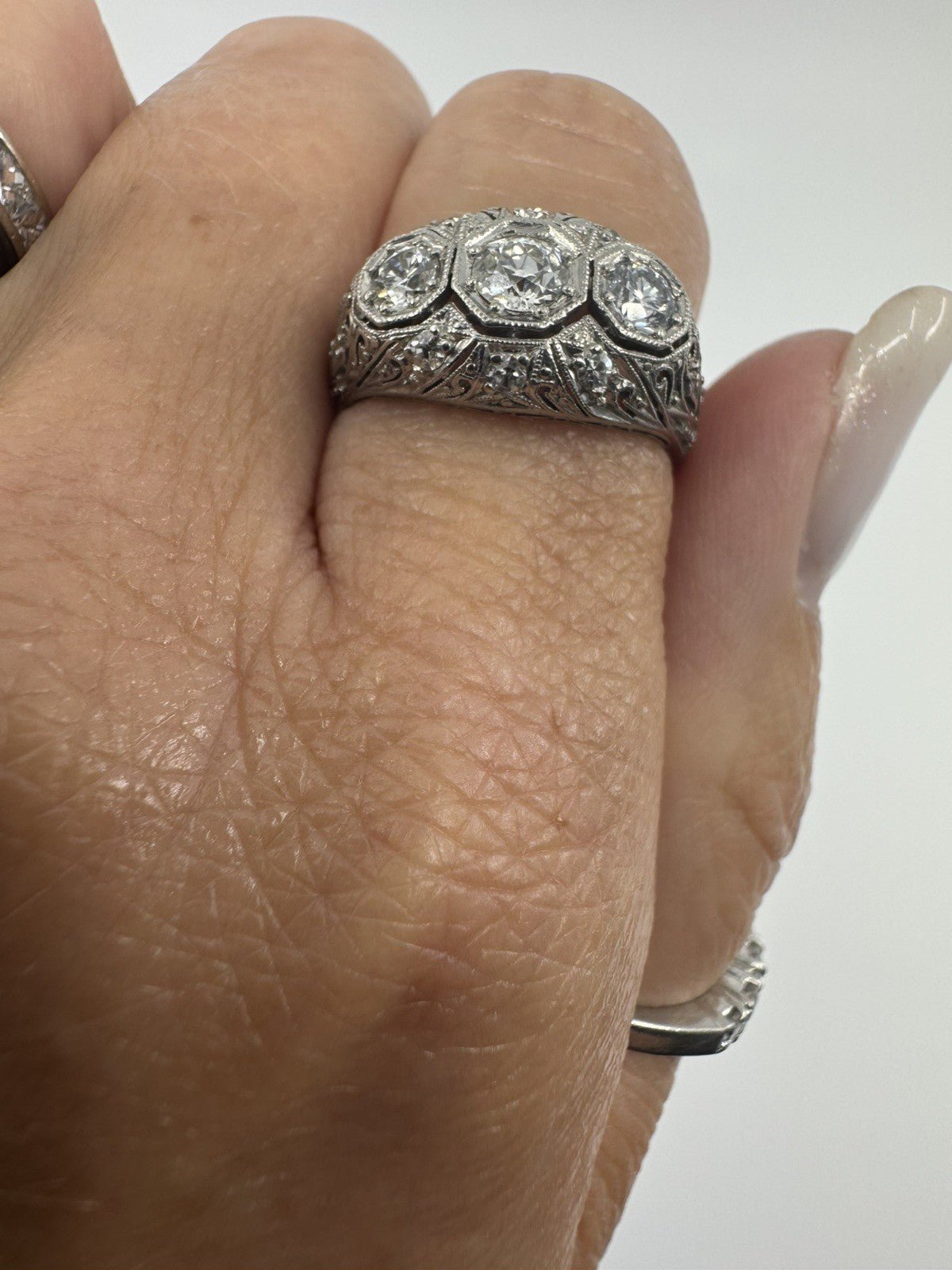 Close up of Art Deco platinum diamond trilogy ring worn on the hand