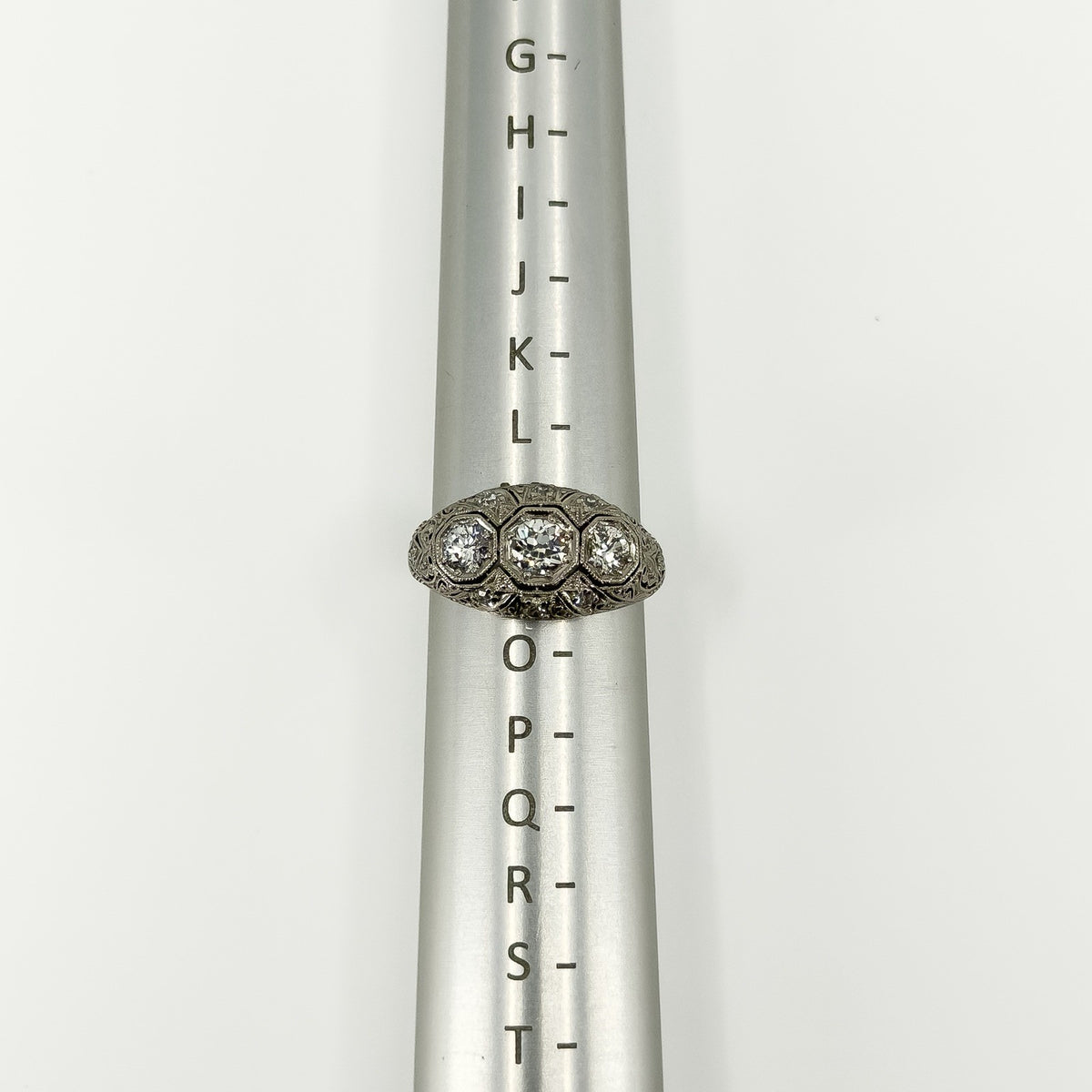 Art Deco platinum diamond trilogy ring shown on a metal ring sizer