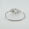 Back angle showing swirl motif and smooth finish of oval silver bangle