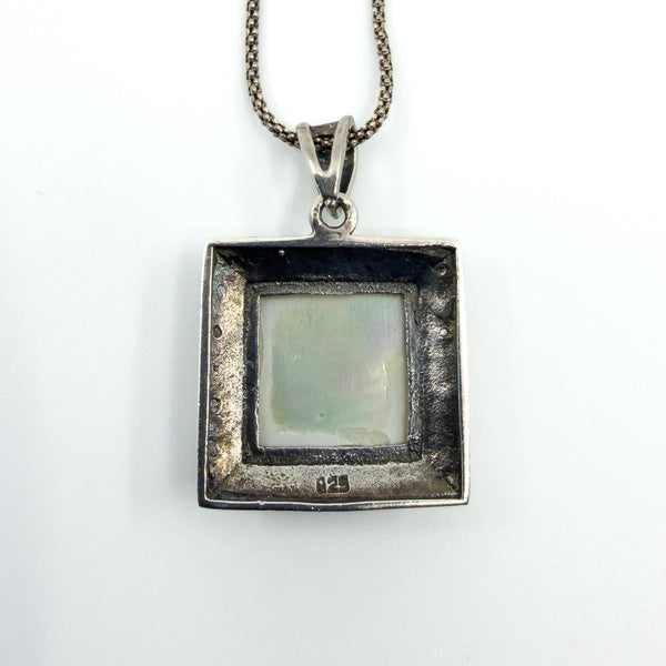 Rear view of the sterling silver pendant with visible 925 stamp and open back behind the mother of pearl.