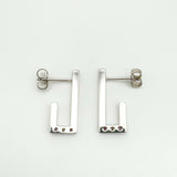 Sterling silver J earrings photographed from the back to show full polished surface and butterfly posts