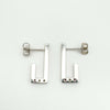 Sterling silver J earrings photographed from the back to show full polished surface and butterfly posts