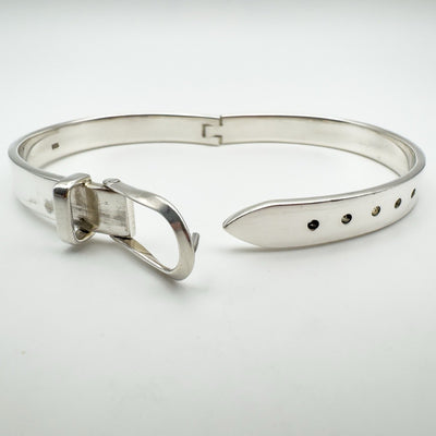 Hinged silver buckle bangle opened to show adjustable holes