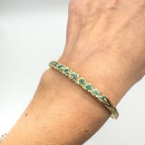 Vintage emerald and diamond bangle worn on wrist, angled view
