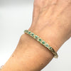 Vintage emerald and diamond bangle worn on wrist, angled view