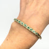 Close-up of vintage gold bangle with emeralds worn on wrist