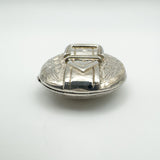 Bottom angle of vintage buckle locket showing engraved floral design