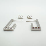 Detail view of bezel set pink sapphires and diamond on sterling silver J hoop earrings