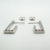 Detail view of bezel set pink sapphires and diamond on sterling silver J hoop earrings