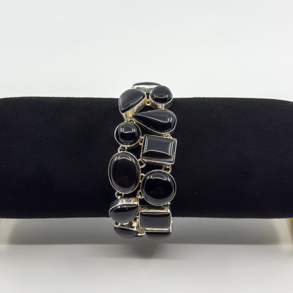 Chunky black onyx bracelet shown on display roll with mixed cabochon stone shapes