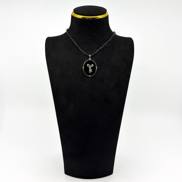 Vintage black onyx and diamond bow pendant shown on a black display bust.