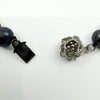Close up of black freshwater pearl necklace clasp with tag and textured front detail