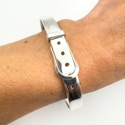 Sterling silver buckle bangle bracelet worn on wrist close-up