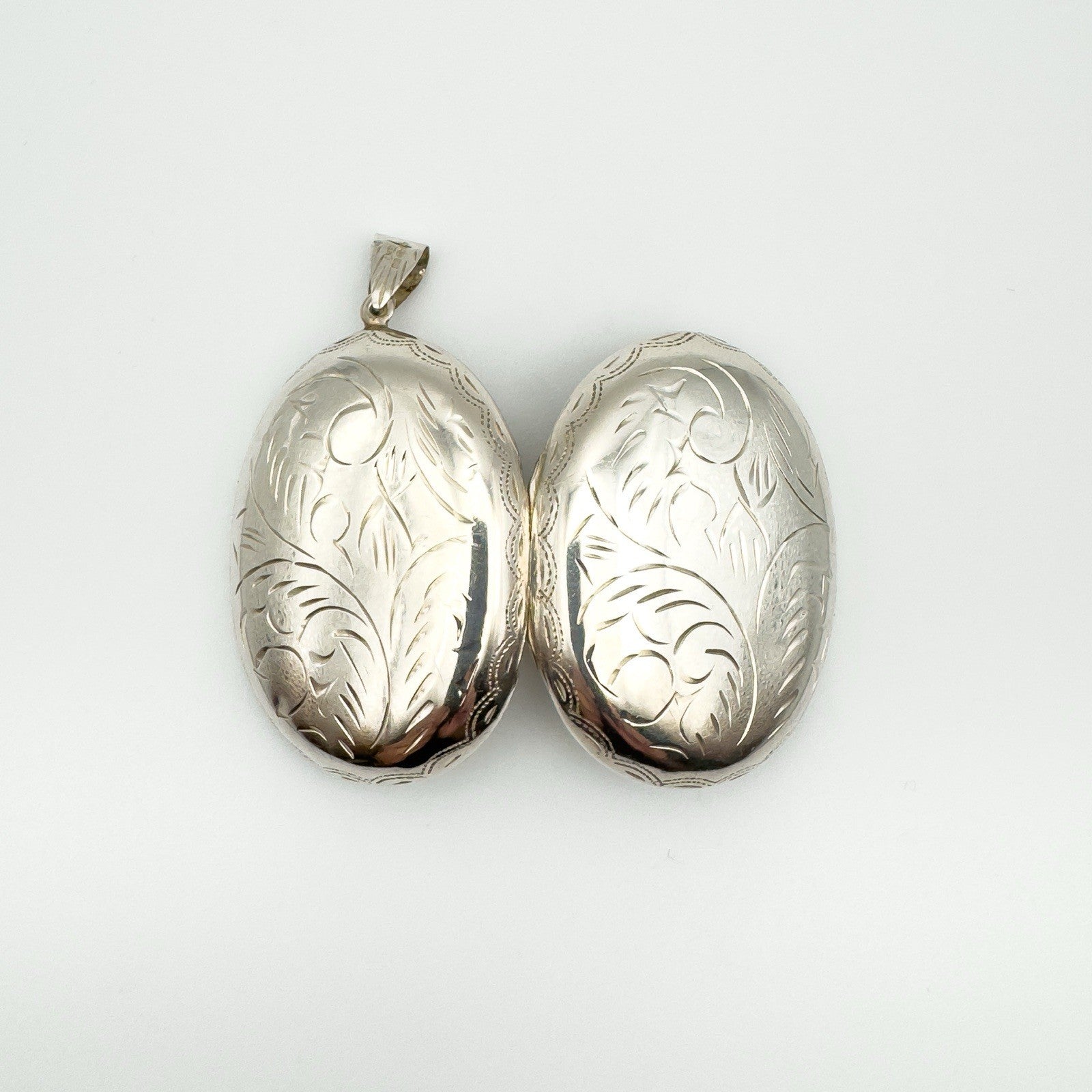 Both sides of silver oval locket with scrollwork design