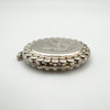 Side angle of vintage sterling silver locket showing engraved face and raised edge