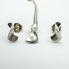 Close-up of pendant and earrings showing diamond and silver swirl shape