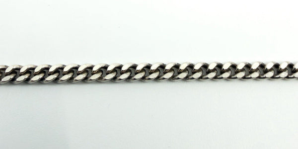 Close-up of the flat link curb chain in sterling silver, showing the polished, low-profile link pattern.