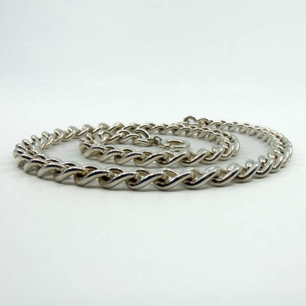 Curb chain coiled to show bolt ring clasp and sturdy links in sterling silver.