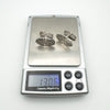 Pair of silver cufflinks placed on scale showing total weight of 13.06g