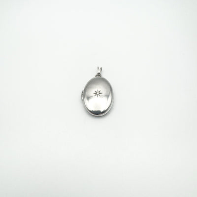 Full view of oval silver diamond starburst locket on white background