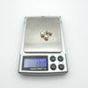 Pair of white pearl earrings on scale showing weight of 1.8g