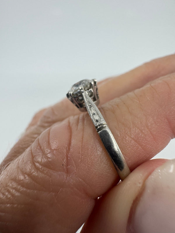 Side view of antique platinum old-cut diamond solitaire ring worn on hand with engraved shoulder detail