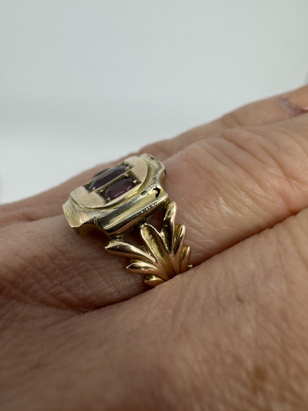 Close worn view of Georgian 9ct gold amethyst ring showing fleur de lis style shank and raised setting